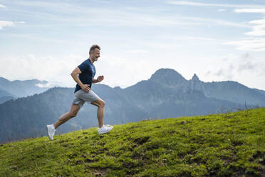 Smiling mature man running on mountain - DIGF16352