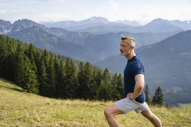 Mann mit Hand auf der Hüfte, der sich beim Sport streckt - DIGF16357