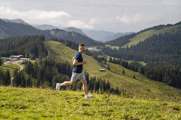 Mature man exercising while running on meadow - DIGF16360