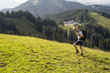 Männlicher Rucksacktourist beim Wandern auf einem Berg an einem sonnigen Tag - DIGF16361