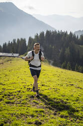 Männlicher Rucksacktourist beim Wandern in den Bergen an einem sonnigen Tag - DIGF16362