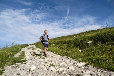 Männlicher Wanderer auf einem Wanderweg an einem sonnigen Tag - DIGF16370