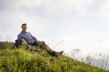 Male hiker resting on mountain during sunny day - DIGF16372