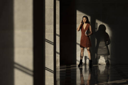 Young woman talking on phone while standing inside passage - EAF00057