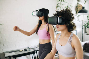 Friends with virtual reality headsets exercising together at home - ASGF01108