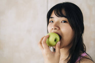 Woman eating apple at home - ASGF01134