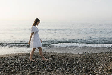 Smiling woman walking at beach - XLGF02203