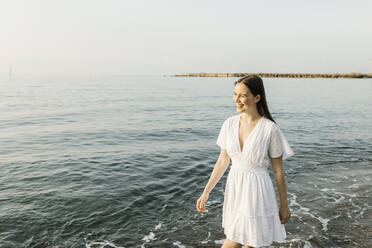 Glückliche junge Frau, die am Strand spazieren geht - XLGF02212