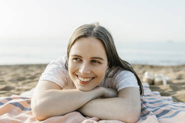 Lächelnde Frau, die auf einem Strandtuch liegt und sich entspannt - XLGF02232