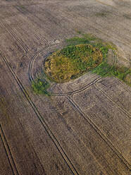 Aerial view of small patch of green left on vast countryside field - KNTF06362