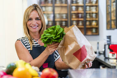 Smiling female owner working at organic store - DLTSF02099