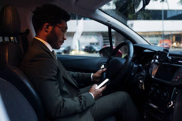 Young businessman using mobile phone while sitting in car - MEUF04161