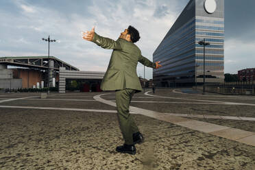 Businessman with arms outstretched spinning on footpath - MEUF04171