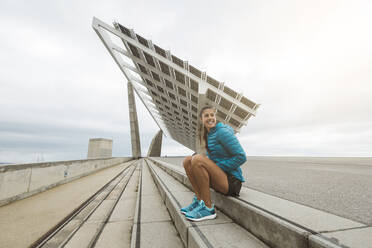 Smiling sportswoman looking away while sitting on steps - MTBF01079