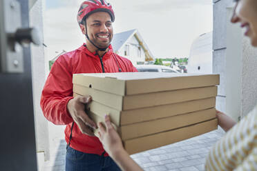 Deliveryman giving pizza order to customer at doorway - ABIF01450