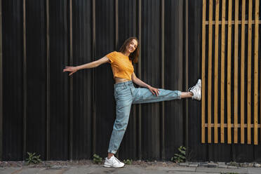 Smiling woman leaning on black color wall - VPIF04609