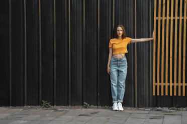 Woman stretching hand while standing on footpath - VPIF04611