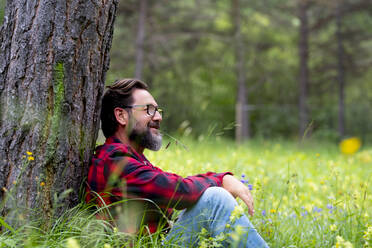 Mature man contemplating while sitting in forest - SIPF02333