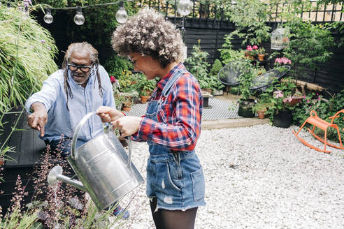 Father talking with daughter while gardening at backyard - ASGF01205