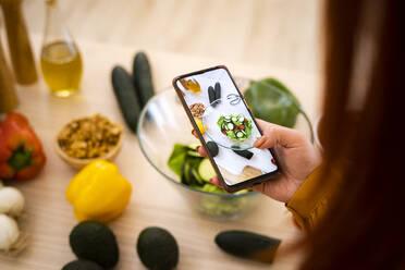 Frau fotografiert Salatschüssel am Tisch mit dem Mobiltelefon - GIOF13231