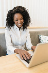 Geschäftsfrau lächelnd bei Videoanruf durch Laptop in Café - JRVF01551
