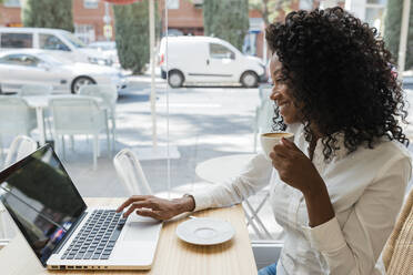 Businesswoman using laptop while having coffee at cafe - JRVF01569
