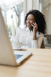 Female freelancer talking on mobile phone at coffee shop - JRVF01577