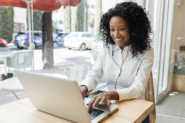 Junge Geschäftsfrau, die einen Laptop benutzt, während sie in einem Café sitzt - JRVF01581