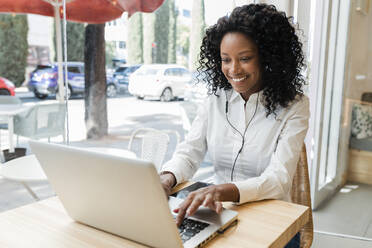 Young businesswoman using laptop while sitting at cafe - JRVF01581