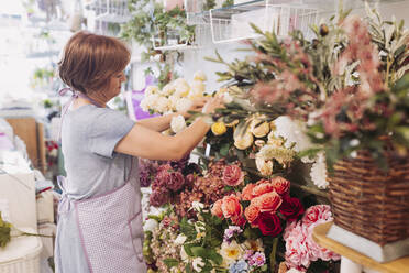 Reife Blumenhändlerin arrangiert Blumen bei der Arbeit im Geschäft - LJF02279
