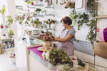 Unternehmerin mit kurzen Haaren arrangiert Blumen bei der Arbeit im Geschäft - LJF02293