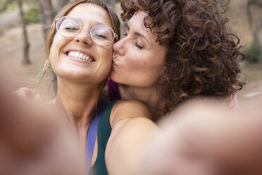 Lächelnde Frau nimmt Selfie mit Freund küssen auf die Wange - JPTF00909