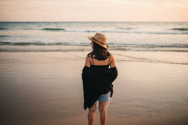 Frau mit Blick auf das Meer bei Sonnenuntergang - GRCF00861