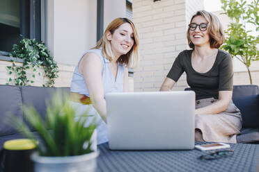 Geschäftsfrauen mit Laptop auf dem Sofa sitzend - MRRF01299