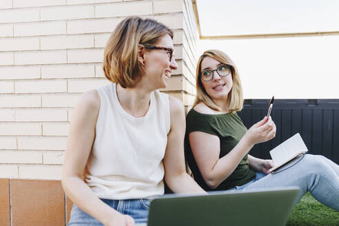 Businesswomen discussing while sitting at terrace - MRRF01308