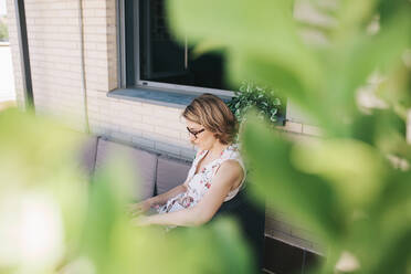 Businesswoman using laptop while working at rooftop - MRRF01316