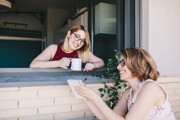 Smiling businesswoman showing note pad to colleague at window - MRRF01319