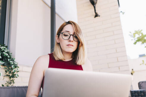 Businesswoman using laptop while working at rooftop - MRRF01323