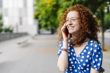 Lächelnde rothaarige Frau, die mit einem Mobiltelefon spricht - JCZF00780