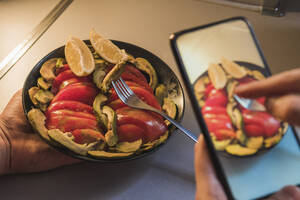 Frau fotografiert Teller mit Avocadosalat, den ihr Freund zu Hause aufbewahrt - MGRF00380