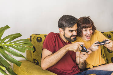 Cheerful couple playing video game at home - MGRF00396