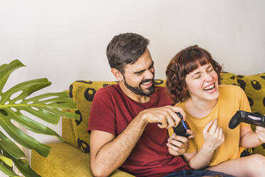 Paar hat Spaß beim Spielen eines Videospiels zu Hause - MGRF00397