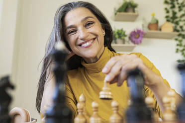 Lächelnde schöne Frau spielt Schach zu Hause - JCCMF03582