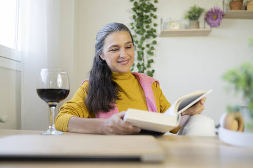 Lächelnde Frau, die zu Hause ein Buch liest - JCCMF03587