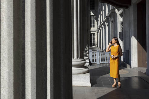 Frau, die mit ihrem Smartphone telefoniert, während sie in der Nähe der Säule der Nationalgalerie in Singapur steht - EAF00070