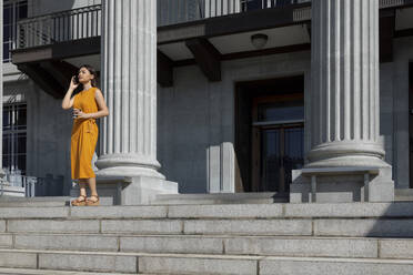 Junge Frau, die mit ihrem Handy spricht, während sie in der Nähe der Säule der Nationalgalerie in Singapur steht - EAF00072