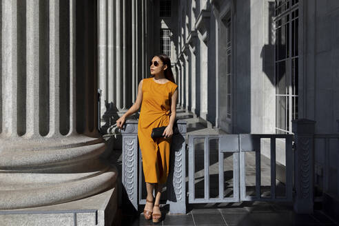 Young woman in sunglasses looking away while leaning on gate at National Gallery, Singapore - EAF00073