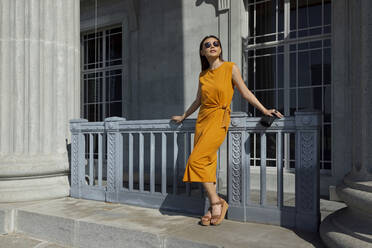 Young woman looking away while standing in front of gate at National Gallery Singapore during sunny day - EAF00075