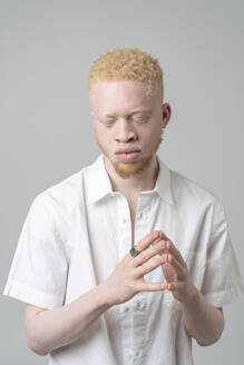 Studio-Porträt eines Albino-Mannes im weißen Hemd mit geschlossenen Augen - ISF24919