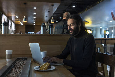 UK, London, Man using laptop at airport cafe - ISF24928